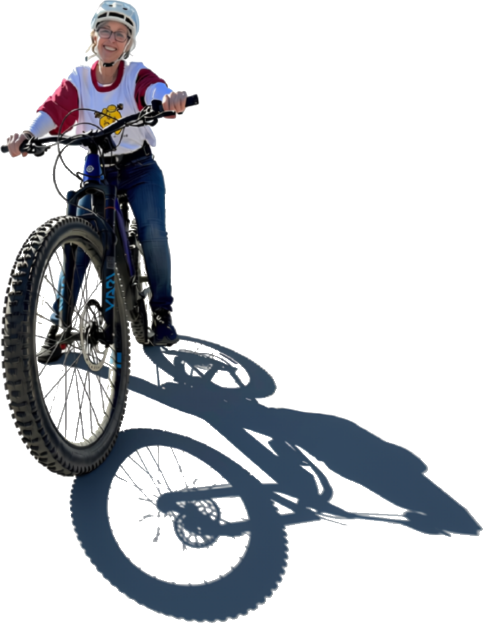Gina Calvert on a mountain bike, smiling, with her shadow stretching behind her